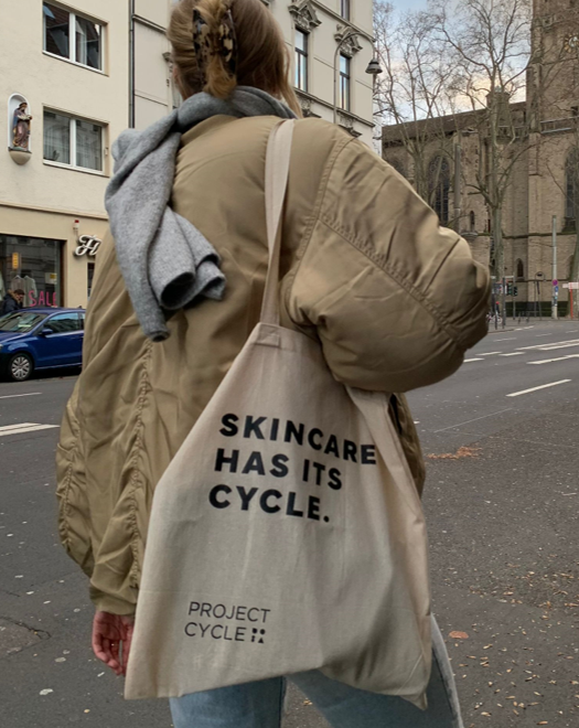 Frau trägt Jutebeutel mit Motto Skincare has its cycle von project-cycle auf der Straße